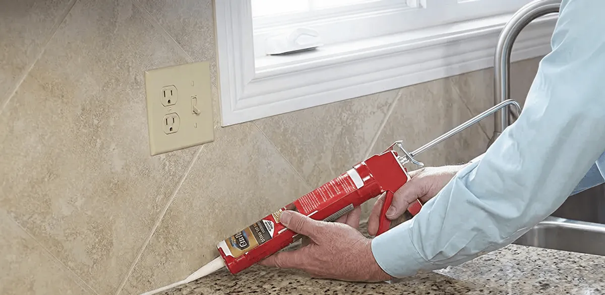 Handyman applying caulk along a kitchen backsplash and countertop seam in Denver, CO