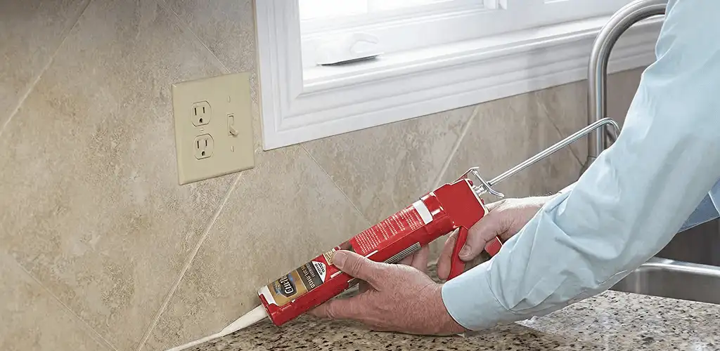 Handyman applying caulk along a kitchen backsplash and countertop seam in Denver, CO