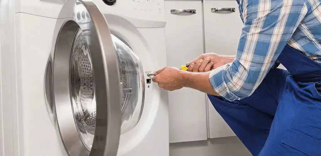 Handyman repairing a clothes dryer and checking electrical connections in Denver, CO