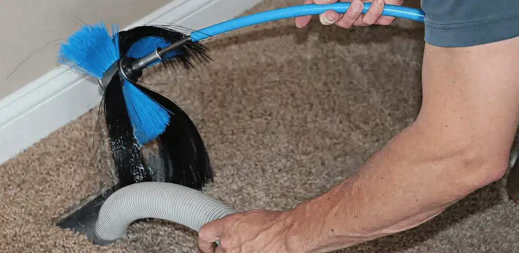 Dryer vent cleaning technician brushing lint from a vent line in Denver, CO