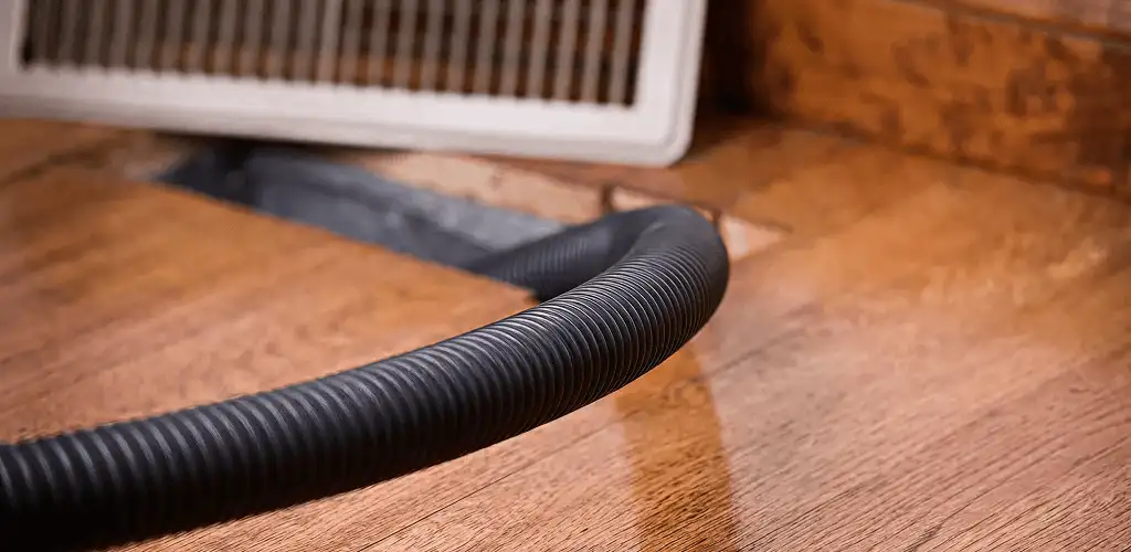 Air duct cleaning hose inserted into a floor vent for ductwork cleaning in Denver, CO