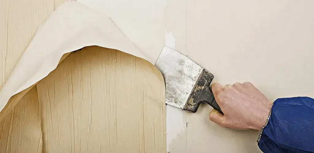 Handyman removing wallpaper with a scraper for wall preparation in Denver, CO