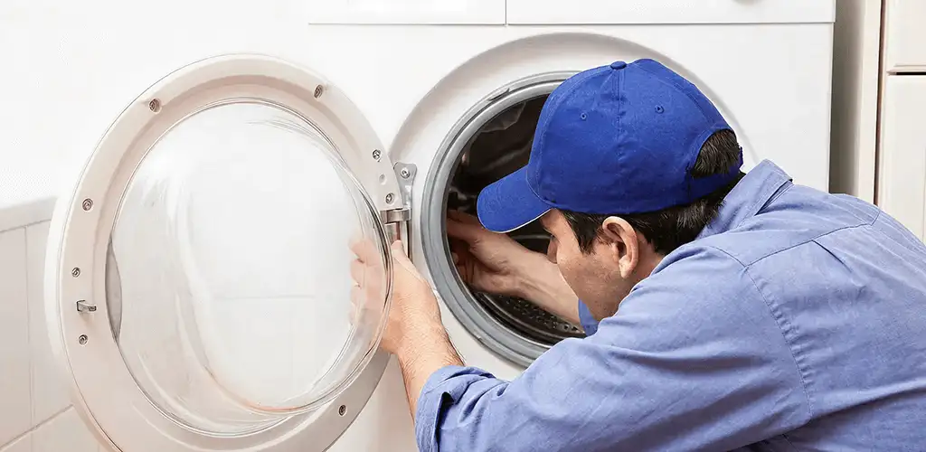Washing machine repair handyman inspecting a front-load washer drum in Denver, CO