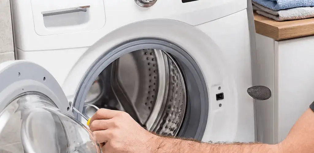 Handyman repairing a front-load washing machine and inspecting the drum in Denver, CO