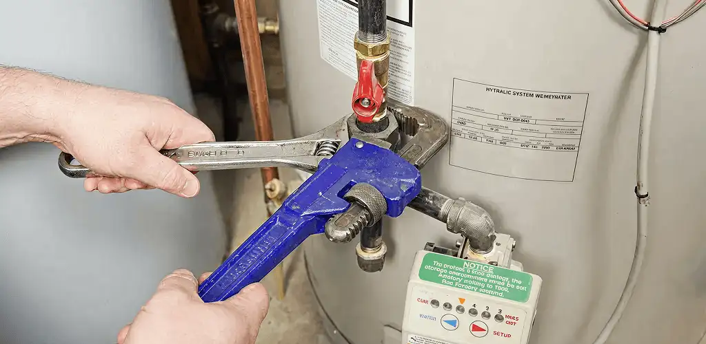 Water heater repair technician tightening the shutoff valve and supply line in Denver, CO
